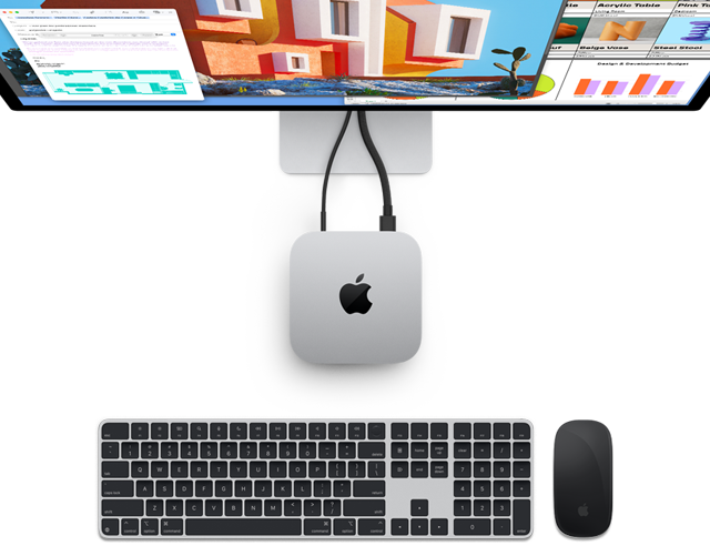 En Mac mini i silver med Apple-logotyp, sedd ovanifrån, ansluten till en bildskärm och bredvid ett trådlöst Magic Keyboard och en Magic Mouse